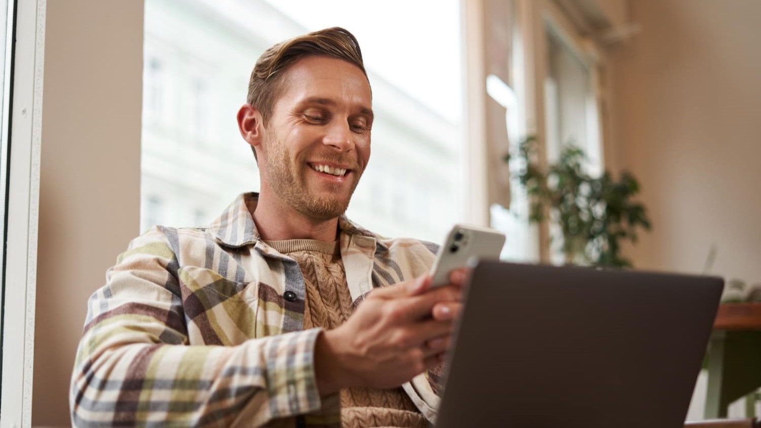 Man ontspant via digitale platforms op smartphone en laptop, symbool voor digitale ontspanning.