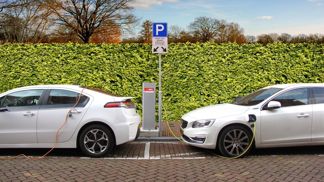 Twee elektrische auto's aan laadpaal op openbare parkeerplaats, onderdeel van stedelijke laadinfrastructuur