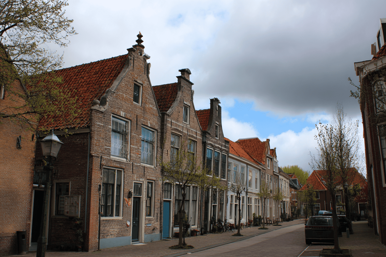 Afbeelding van een straat in Nederland met typisch Nederlandse huizen.