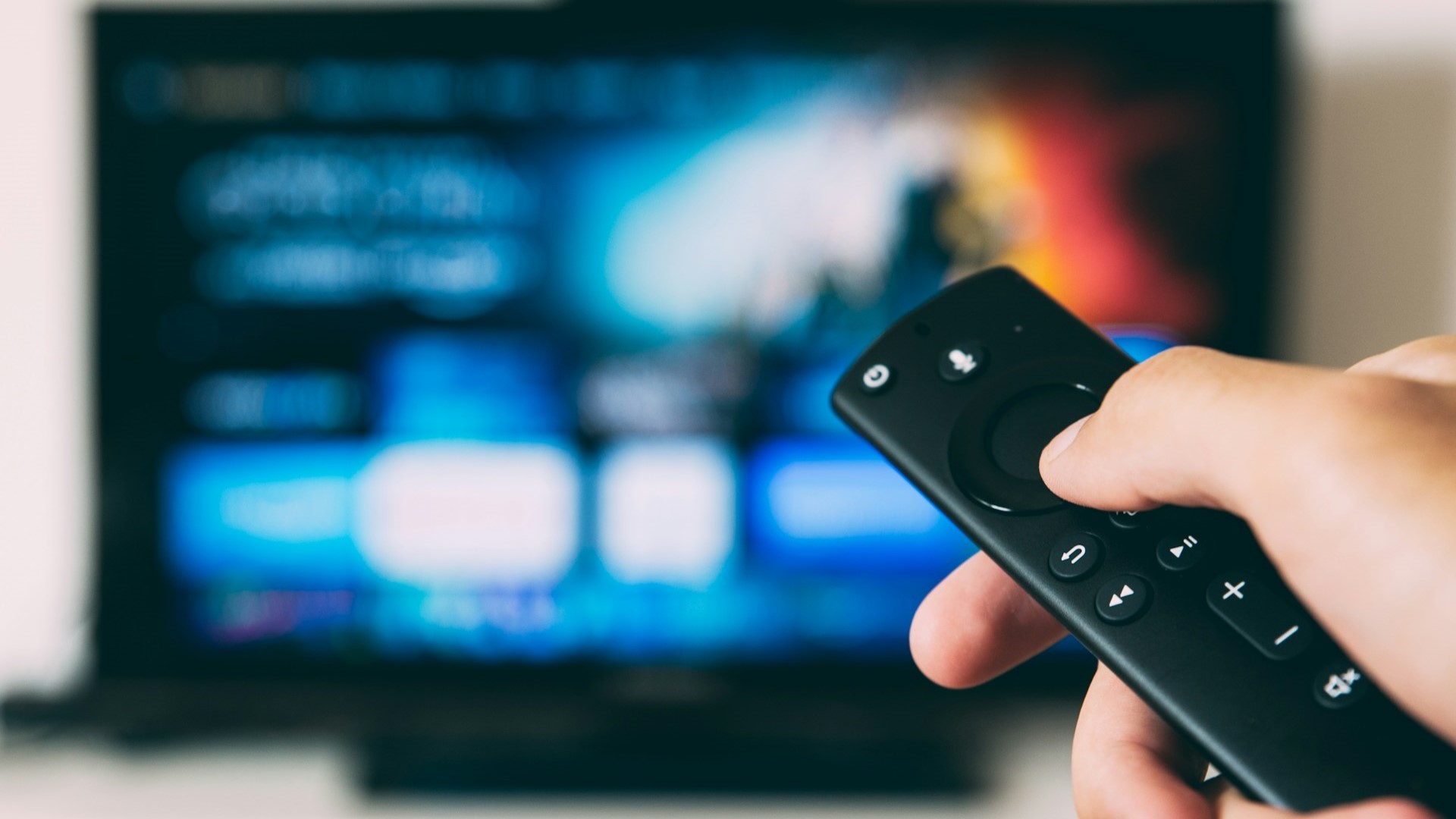 Hand met afstandsbediening richt op smart-tv met instant entertainment apps op het scherm