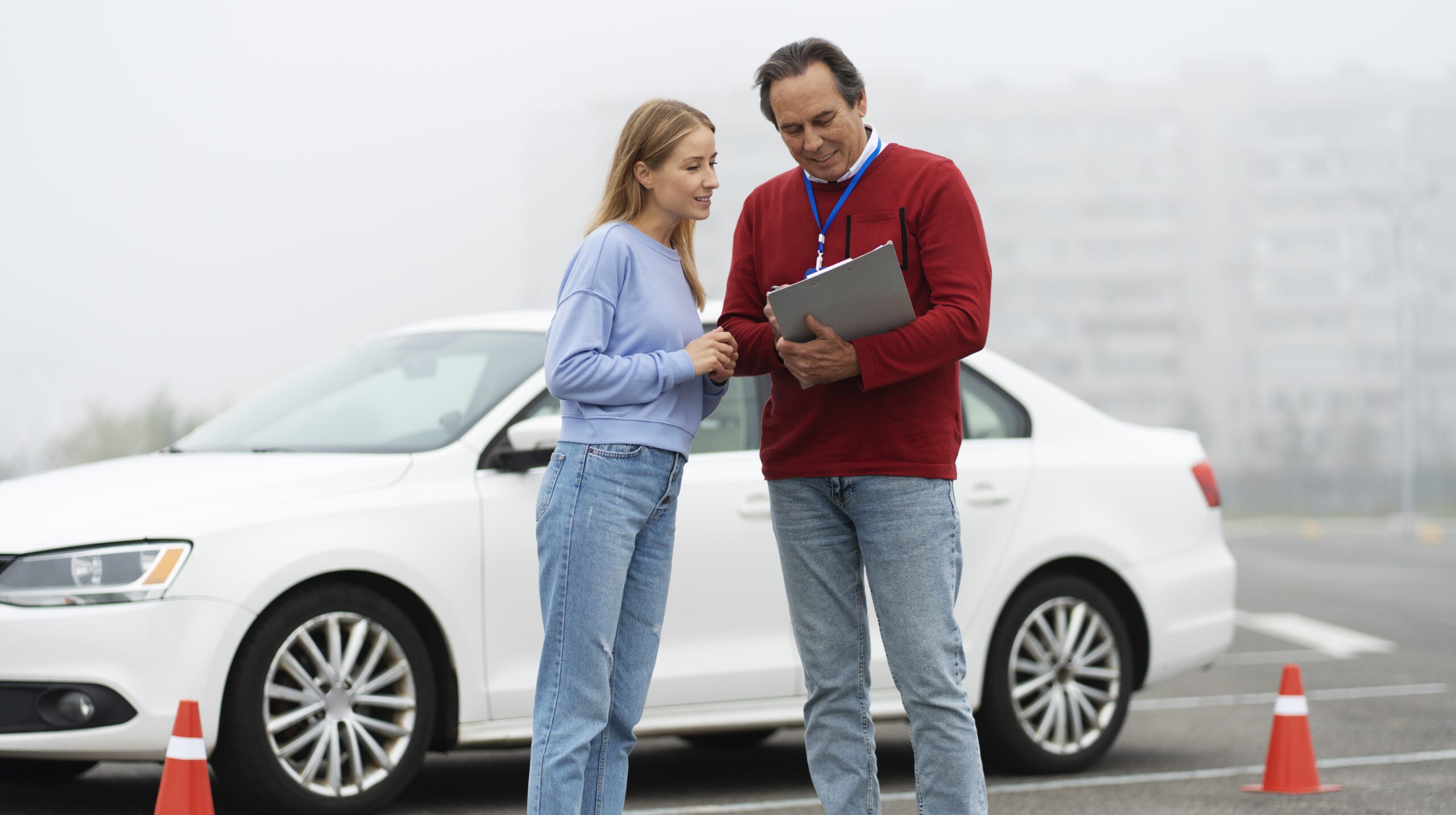 Leerling en rijinstructeur bespreken examenuitslag naast lesauto met pionnen op oefenterrein – wachttijden CBR