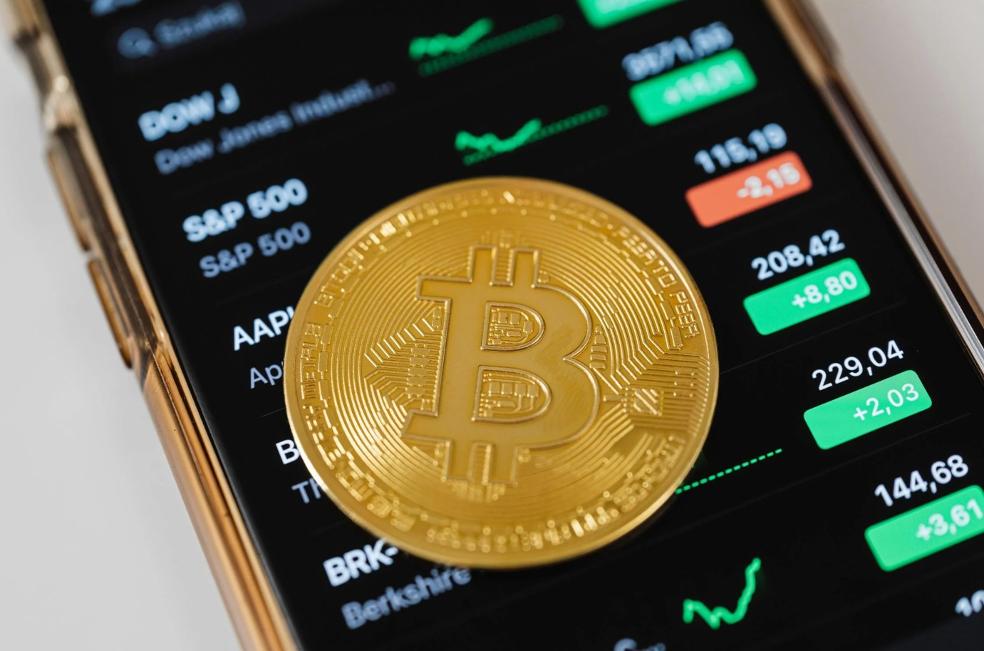 Gouden bitcoin-munt op smartphone met koersdata, passend bij trading strategieën