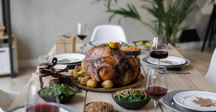 Geroosterde kalkoen als middelpunt van een feestelijke tafel met bijgerechten en rode wijn.