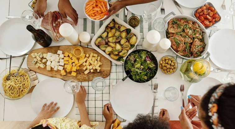 Gezellig diner met verschillende gerechten zoals kaas, salade, wortels en gebraden kip op een feestelijke tafel.