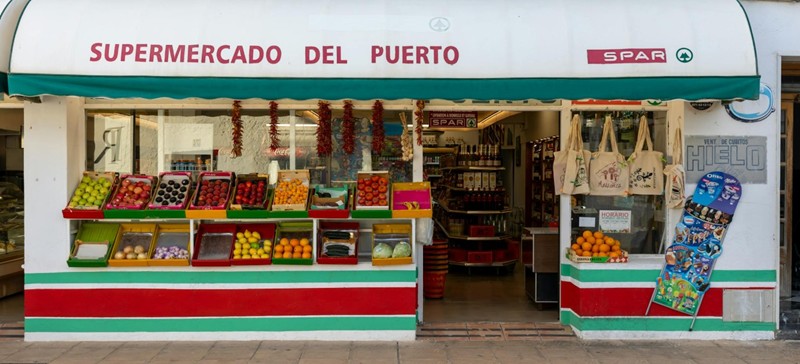 Buitenkant van een kleurrijke Spaanse supermarkt met vers fruit in bakken voor de ingang
