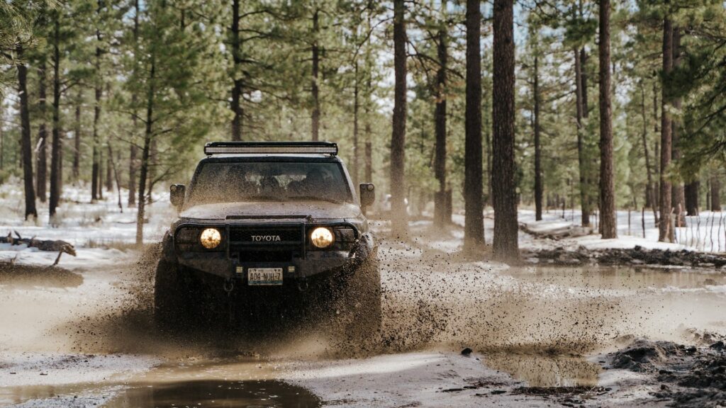 4x4-onderdelen in actie tijdens offroad rijden door modder met opspattend water en zware belasting