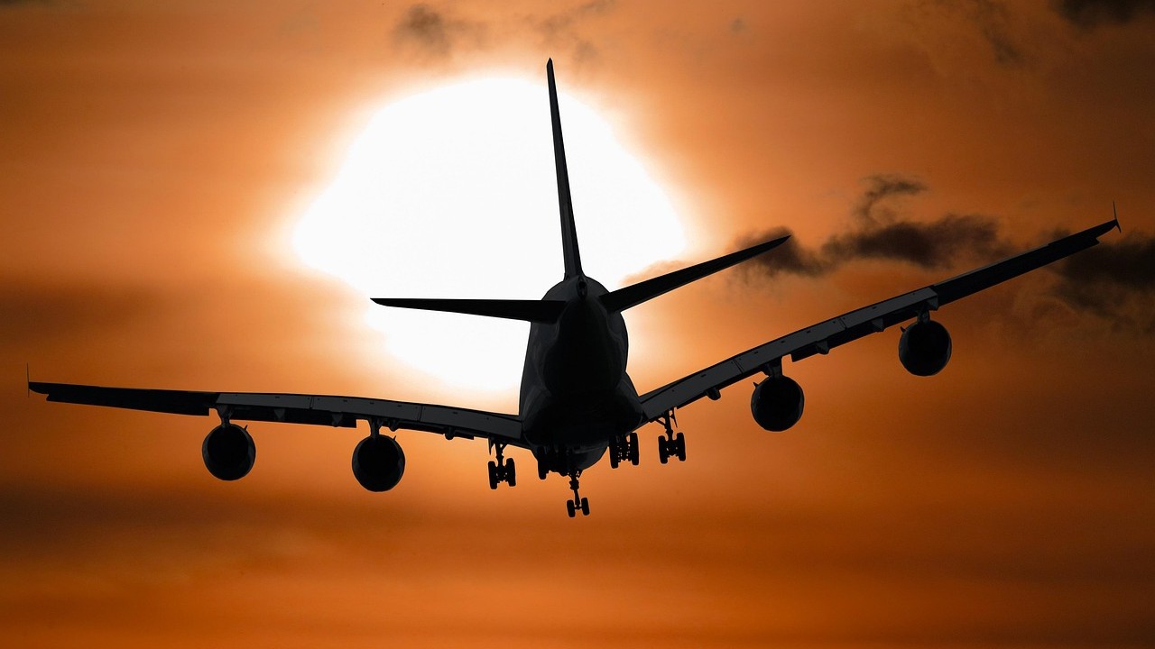 Vliegtuig bij zonsondergang tijdens goedkope reizen Europa met silhouet tegen oranje lucht