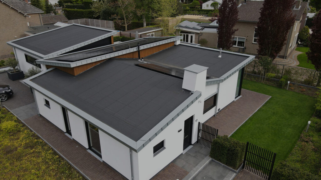 Een moderne woning met een plat dak, gezien van bovenaf in een rustige woonwijk.