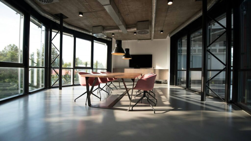 Moderne vergaderruimte met grote ramen, houten tafel en industriële inrichting