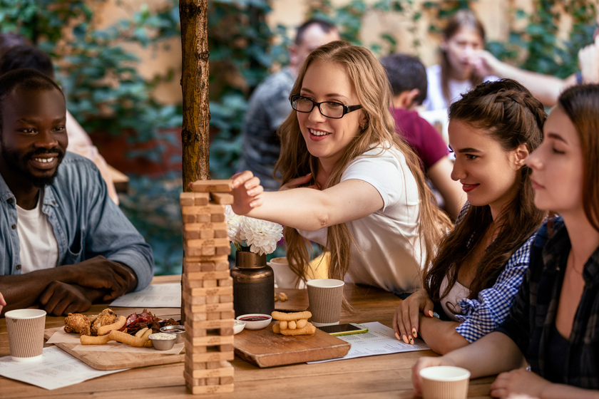 Vrienden spelen Jenga aan tafel tijdens een schermvrije activiteit.